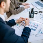 Business team analyzing financial graphs at a meeting table, fostering collaboration in an office environment.
